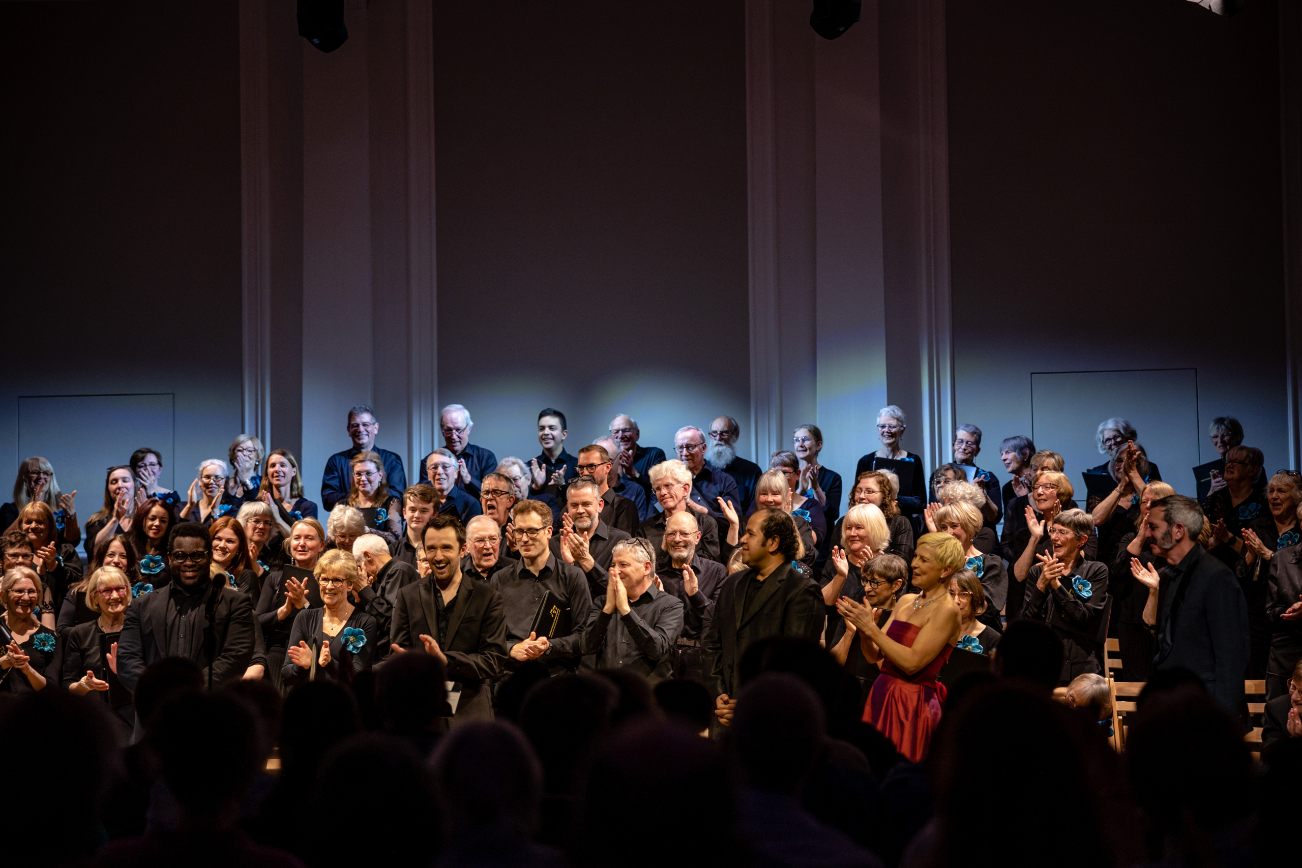 Smiling choir, conductor, pianist and soloists receiving applause after concert